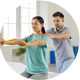 A man and woman engaged in physical therapy exercises together in a well-lit therapy room, focusing on their movements.