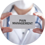 A man wearing medical scrubs and a stethoscope around his neck holds a small card with "pain management" written on it