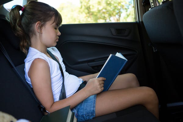 girl reading book in car