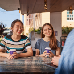 Two students sitting with a takeaway coffee 