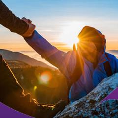 An image of a hiker helping another hiker up a cliff