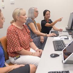 A staff member teaching a group of people with aphasia how to use computers