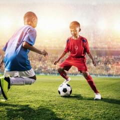 Two children playing soccer, one is changing directions quickly.