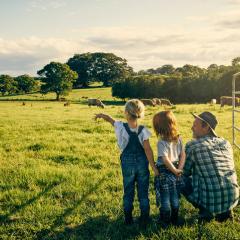 father and two daughters looking over farm 
