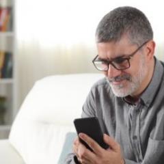 man sitting on couch scrolling through phone