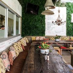 A wooden table in a trendy cafe with a menu on a garden wall in the background
