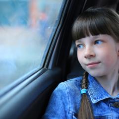girl looking out window of car